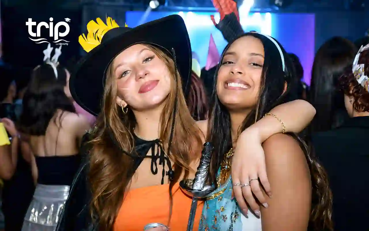 Duas formandas fantasiadas na Festa à Fantasia, uma com chapéu de bruxa