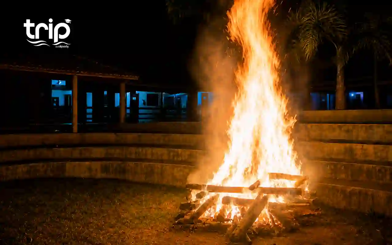 Fogueira acesa à noite no Luau da Trip, com coqueiros ao fundo