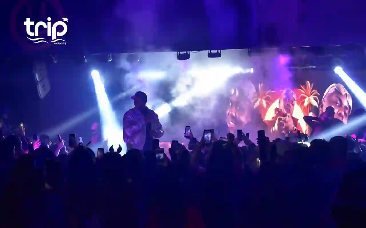 Palco iluminado durante o show, com a plateia em pé filmando com o celular